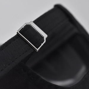 Macro view of the black cotton baseball cap's adjustable silver metal buckle and strap
