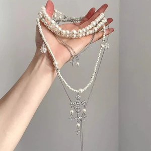 Detailed close-up of layered baroque pearl necklace with diamond-encrusted silver crosses