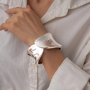 Detail of silver irregular pleated cuff bracelet with hammered texture and mirror finish