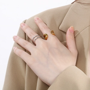 Detail of layered silver ring and golden wave band on finger with minimalist suit style