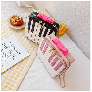 Detail of sweet piano keyboard crossbody bags with bow decoration and gold chain straps