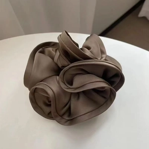 Close-up of a large brown satin silk scrunchie with layered ruffles and soft glossy finish