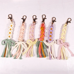 Close-up of handmade woven daisy flower keychains with colorful tassels and gold clasps