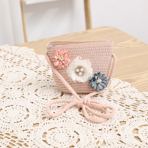 Dettaglio di borsa in paglia rosa con fiori fatti a mano e perle per bambina