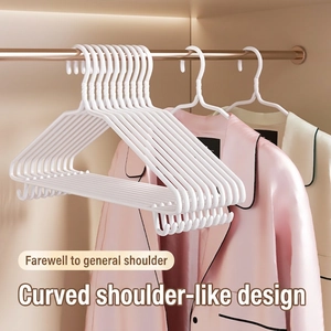 White non-slip plastic clothes hangers with wide shoulder design in a wooden wardrobe