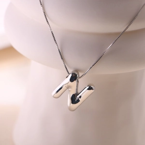 Macro detail of silver balloon style letter N pendant with high-shine polished finish