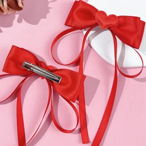 Sweet red ribbon bow hair clips with heart charms for girls on a soft pink background