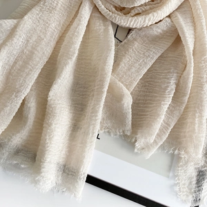 Detailed macro view of beige pleated linen scarf fabric with raw frayed edges and soft texture
