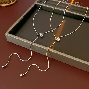 Detail of gold and silver snake chain necklaces with zircon pendants on leather tray