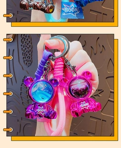 Detail of space bear keychains in purple and pink with liquid glitter helmets and strap