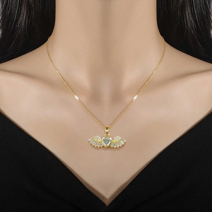 Macro shot of gold angel wing necklace with light blue heart pendant on female model