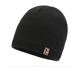 Detail of black winter knit beanie with ribbed cuff and brown leather logo patch