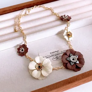 Floral necklace set with layered metal flowers in a brown jewelry display box