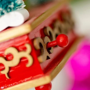 Détail macro du levier rouge et motifs dorés sur une boîte à musique en bois festif