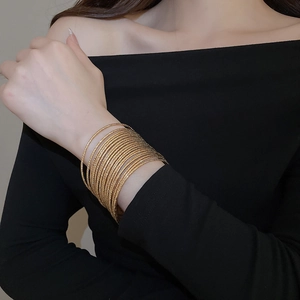 Close-up of twenty gold stackable bangles with textured finish on a female model