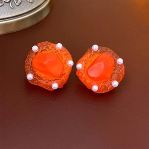 Macro view of vintage style earrings with orange textured resin and tiny white pearls