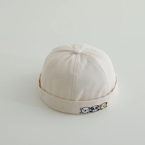 Detail of baby landlord cap in off-white cotton with cute animal embroidery pattern