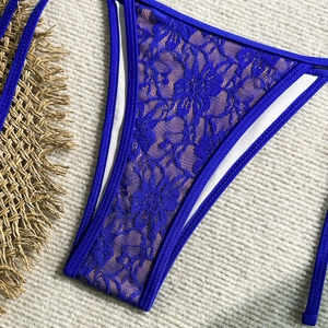 Detail of royal blue floral lace bikini bottom with refined stitching on a woven background