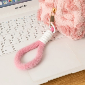 Detail of pink plush makeup bag with golden metal zipper on a white laptop keyboard
