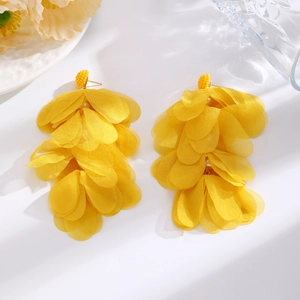 Close-up of yellow raffia flower earrings with layered petals and white pearl bead details