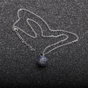 Detail of blue spotted natural stone pendant with silver chain on black background