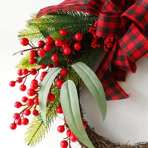 Christmas wreath with red berries, pine needles, natural cones and buffalo plaid bow decoration