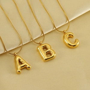 Three gold bubble initial necklaces on silk, featuring letters A, B, and C with snake chains
