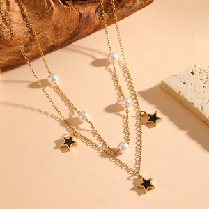 Detail view of double-layer gold necklace with pearls and black star pendants on wood