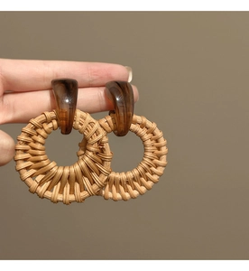 Macro detail of geometric rattan drop earrings with amber-toned resin accents