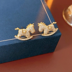 Macro detail of gold horse stud earrings with sparkling crystals on jewelry box