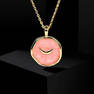 Detail of pink enamel heart pendant with golden wings on a gold necklace chain