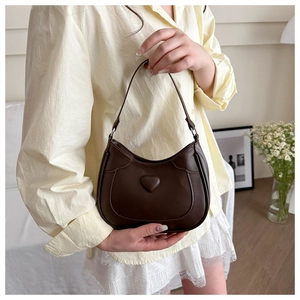 Detail of dark brown crescent handbag with heart embossing and smooth PU leather texture