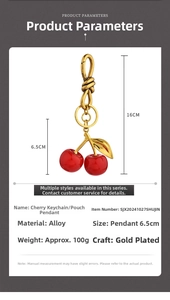 Detailed view of red resin cherry keychain pendant with gold leaf and alloy clasp