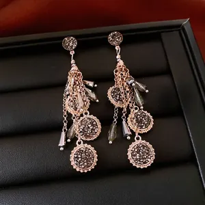 Boucles d'oreilles ethniques dorées à pompons et cristaux sombres en boîte à bijoux