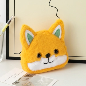 Detail view of cartoon fox plush coin purse with embroidery on a warm background