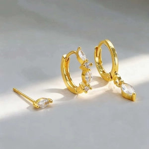 Detailed close-up of gold star and moon earrings set with marquise cut zircon stones