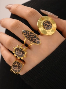 Close-up of four 18K gold rings with leopard print inlay worn on a model's hand