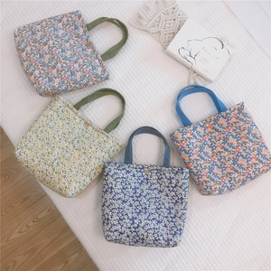 Close-up of four floral canvas tote bags with metal button closure and handles