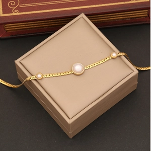 Golden necklace with round faux pearl and diamond halo on beige jewelry box