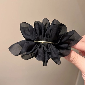 Detail of elegant black mesh pleated hair clip featuring a slim gold metal decorative bar