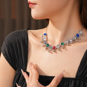 Detail of vintage silver necklace with colorful floral gemstones and bell tassels on model