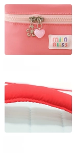 Detailed close-up of pink fabric cosmetic bag with heart-shaped zipper and logo label