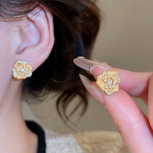Macro shot of gold floral earrings with white crystals showing fine vintage craftsmanship