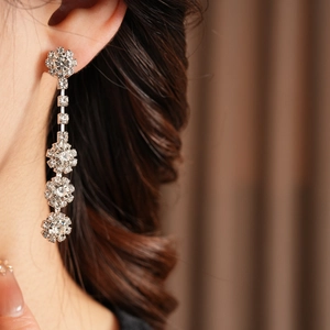 Close-up of diamond-encrusted flower tassel earrings on a model for a luxury look