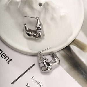 Detailed view of silver liquid metal texture hoop earrings on a minimalist white tray