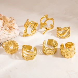 Gold-plated stainless steel rings with irregular lava and pearl designs on marble
