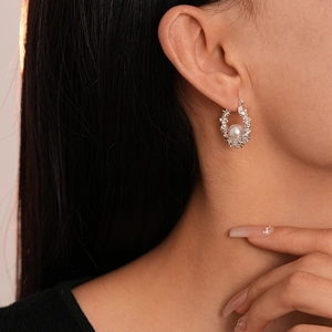 Gros plan d'une boucle d'oreille en perle argentée texturée portée par un mannequin