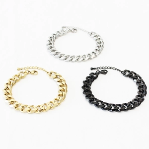 Flat lay of three chunky Cuban link bracelets in silver, gold, and black stainless steel