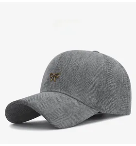 Détail de la casquette grise en tissu à chevrons avec nœud en métal doré