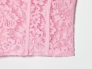 Detailed close-up of pink lace fabric with floral patterns and corset boning structure